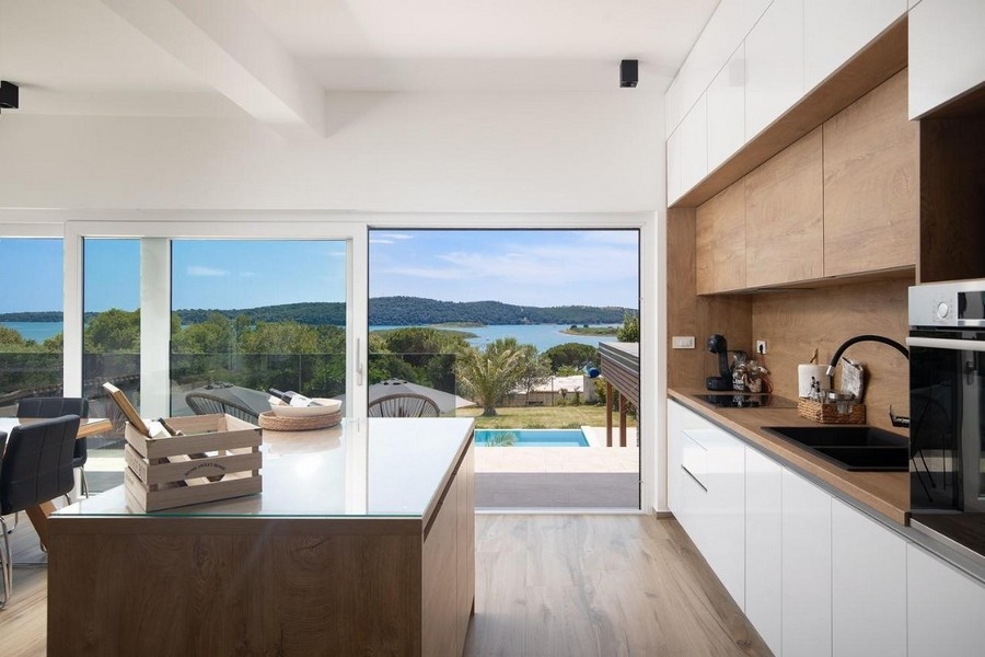 Moderná kuchyňa s výhľadom na bazén a more.