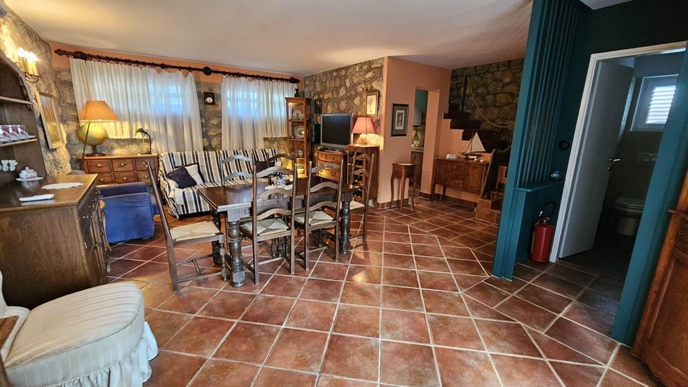 Útulná obývacia izba s jedálenským kútom, kamennou stenou a dreveným nábytkom