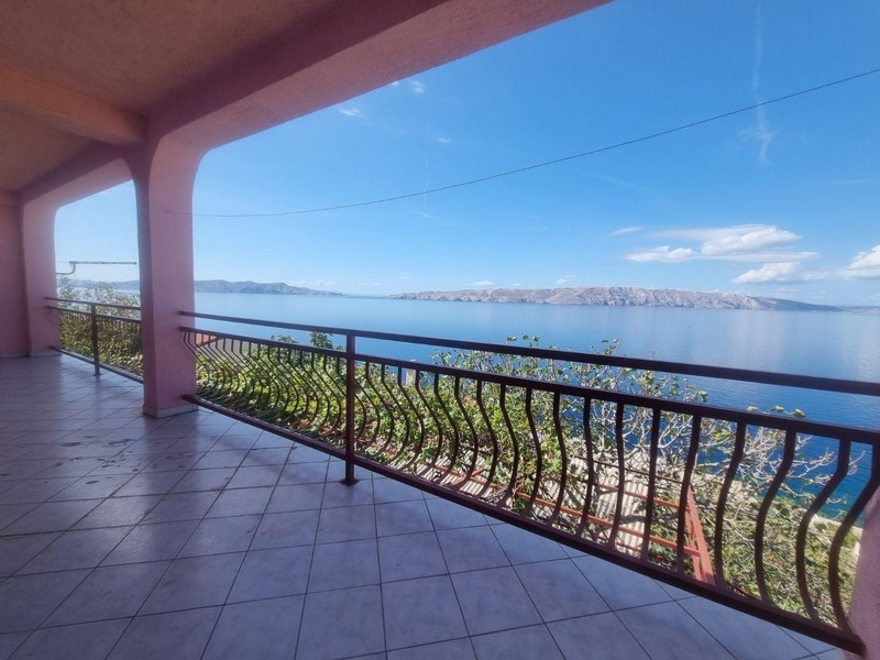 Priestranná terasa s výhľadom na more so zakriveným zábradlím pod krytým priestorom.