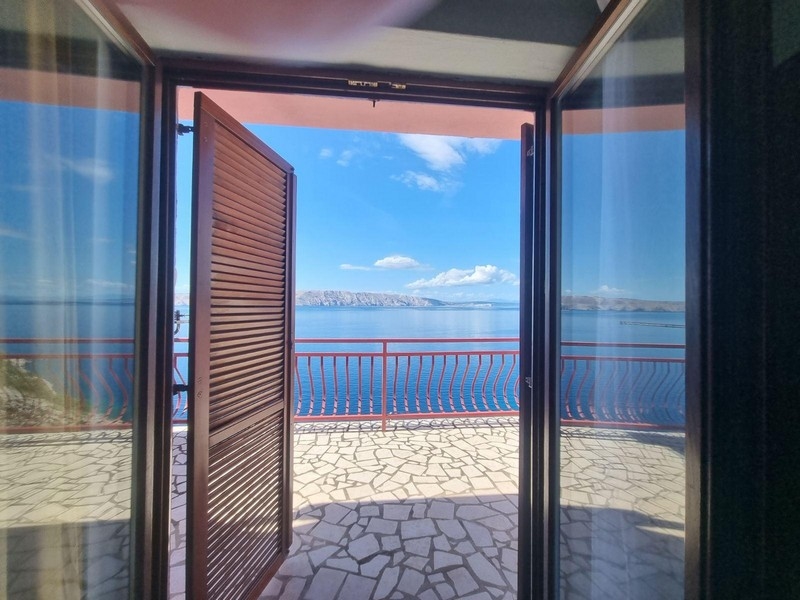 Výhľad z izby cez otvorené dvere na terasu s výhľadom na more.