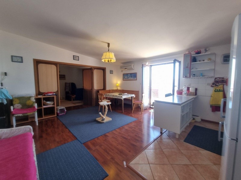 Otvorená obývacia izba s drevenými podlahami a priamym vstupom na terasu, pohodlným posedením a jedálenským kútom.