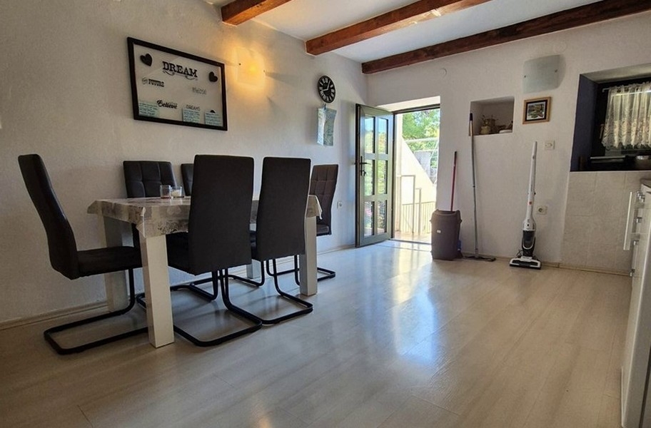 Svetlá jedáleň s moderným nábytkom a drevenými trámami.