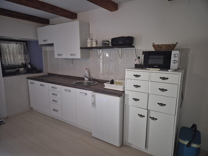 Moderná biela kuchyňa s malými skrinkami a policami.