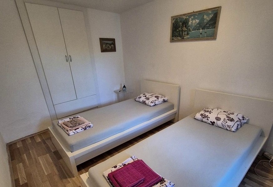 Spálňa s dvoma jednolôžkami a jednoduchým nábytkom.