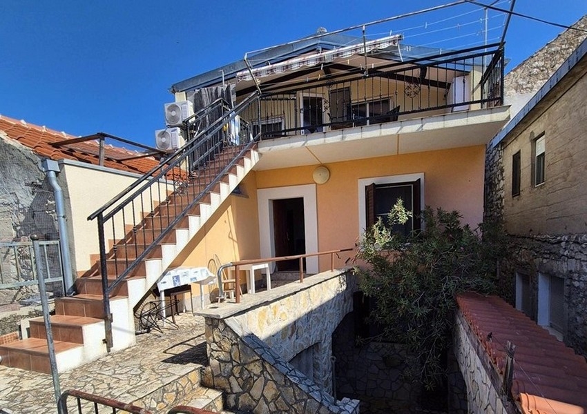 Zadný pohľad na stredomorský kamenný dom s vonkajšími schodmi a terasou.