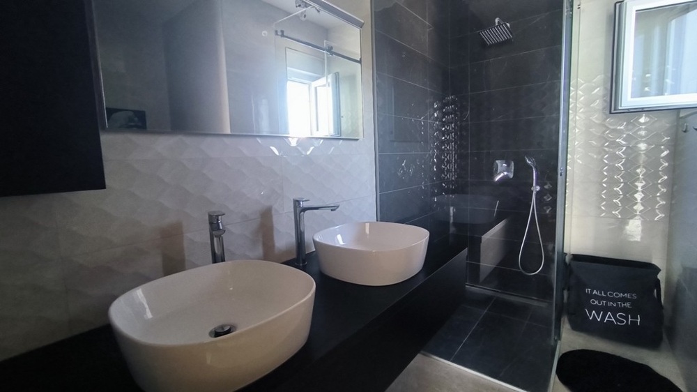 Moderná kúpeľňa s dvojitým umývadlom a dažďovou sprchou.