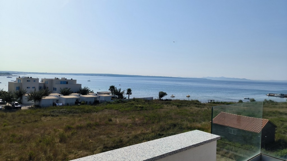 Výhľad na more z terasy s priľahlými domami a prírodou.