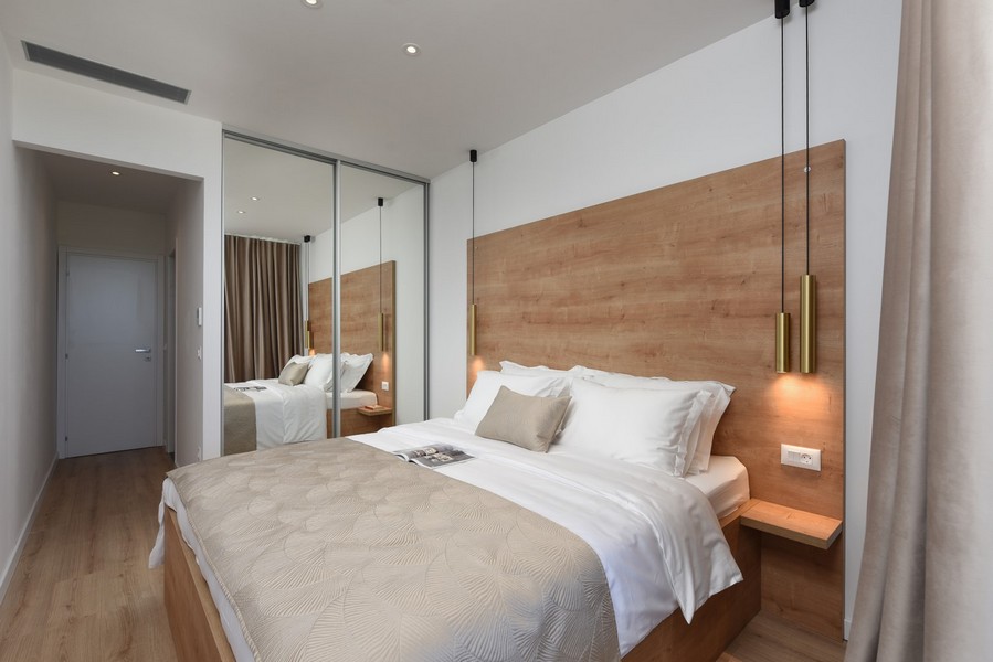 Útulná spálňa s drevenými dekoráciami, zrkadlovou skrinkou a priamym prístupom na balkón.