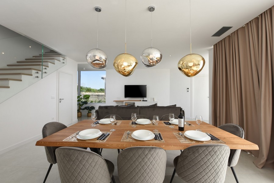 Moderný jedálenský kút s dreveným stolom a dizajnovými lampami v otvorenom obytnom koncepte.