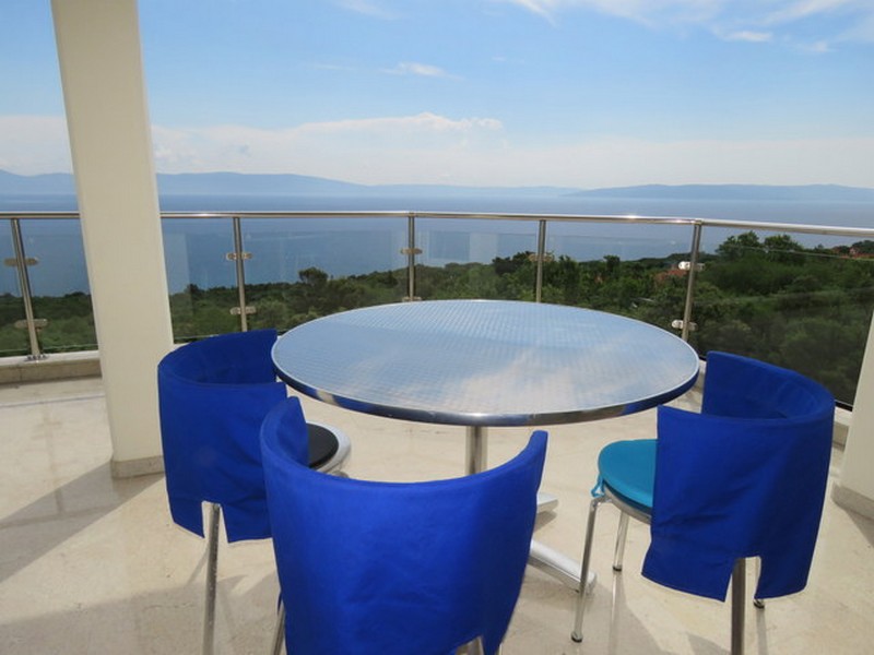 Balkón s krásnym výhľadom na more a jedálenský kút s modrými stoličkami.