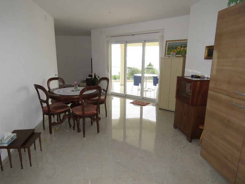 Jedálenský kút s okrúhlym stolom a prístupom na terasu s výhľadom na more.