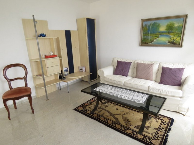 Útulná obývačka s policou a dekoračným kobercom.