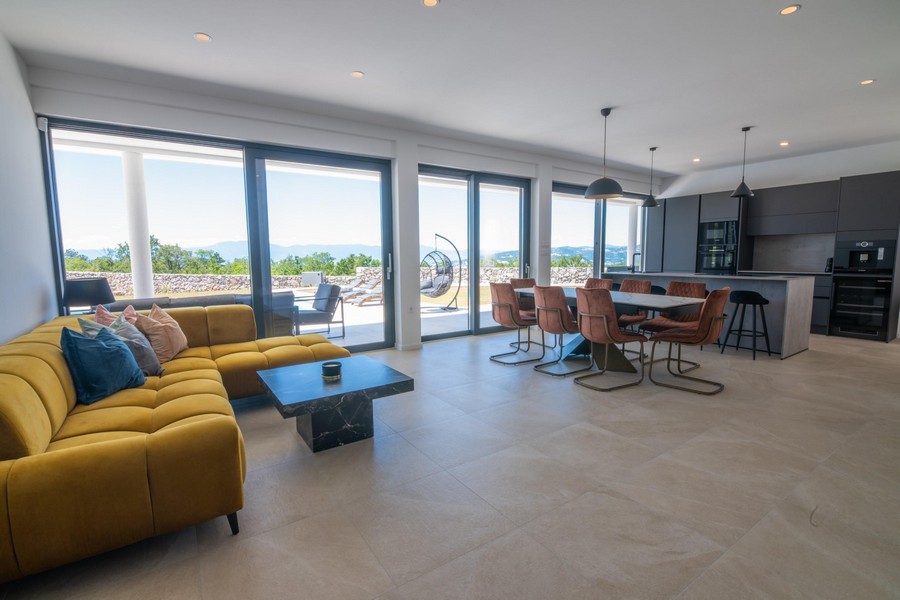 Obývacia izba so žltou pohovkou, jedálenským kútom a otvorenou kuchyňou, panoramatické okno