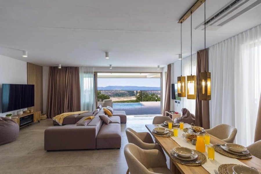 Moderná a luxusne zariadená obývacia izba s jedálenským kútom a výhľadom na bazén.