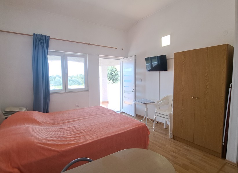 Spálňa s posteľou, TV a dverami na vonkajšiu terasu.