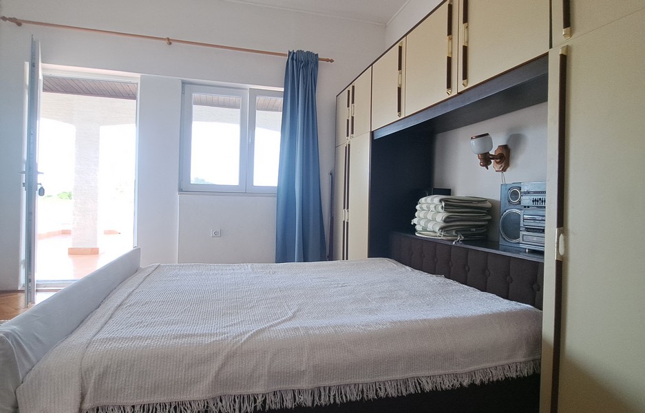 Spálňa s posteľou a vstavaným úložným priestorom, výhľad na vonkajšiu terasu.