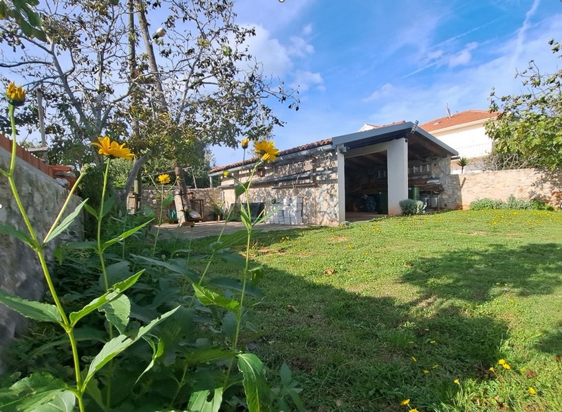 Vonkajší priestor s trávnikom, stromami a kamennou konštrukciou.