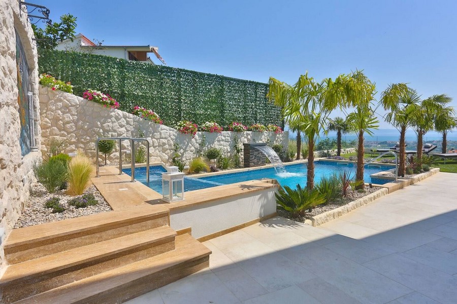 Moderný bazén s vodopádom a palmami