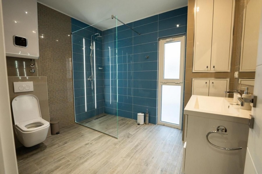 Veľká kúpeľňa so sprchovacím kútom a modrými dlaždicami