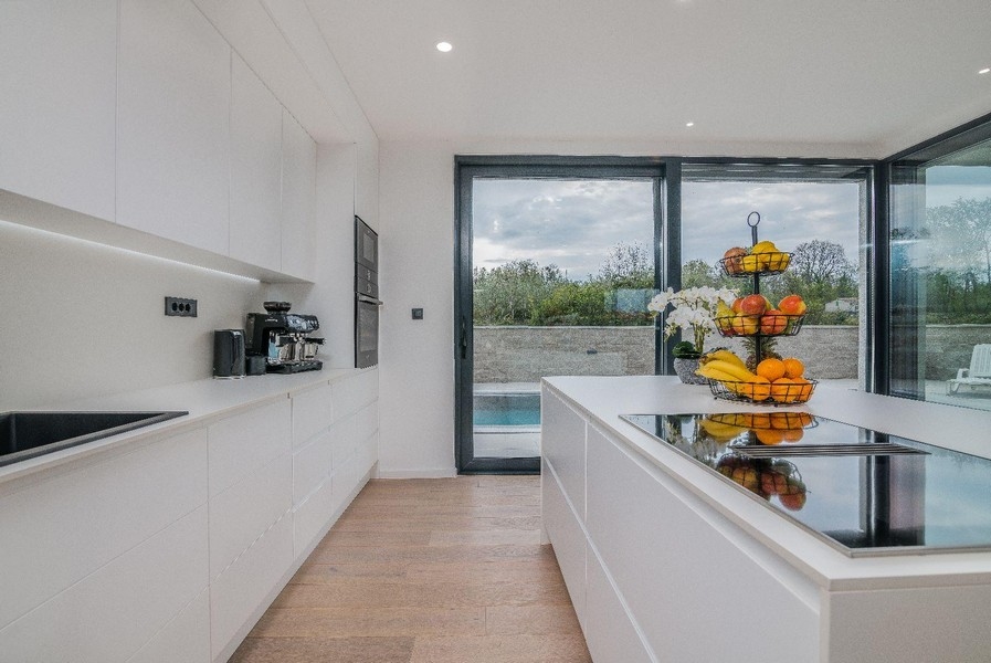 Moderná biela kuchyňa s výhľadom na ostrov a bazén