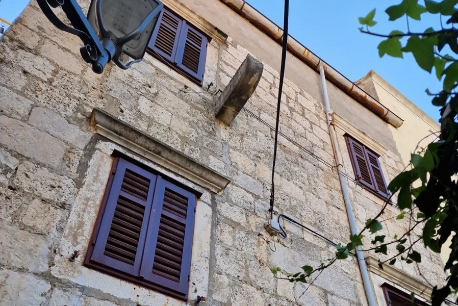 Fasáda kamenného domu s okenicami a stenami z prírodného kameňa