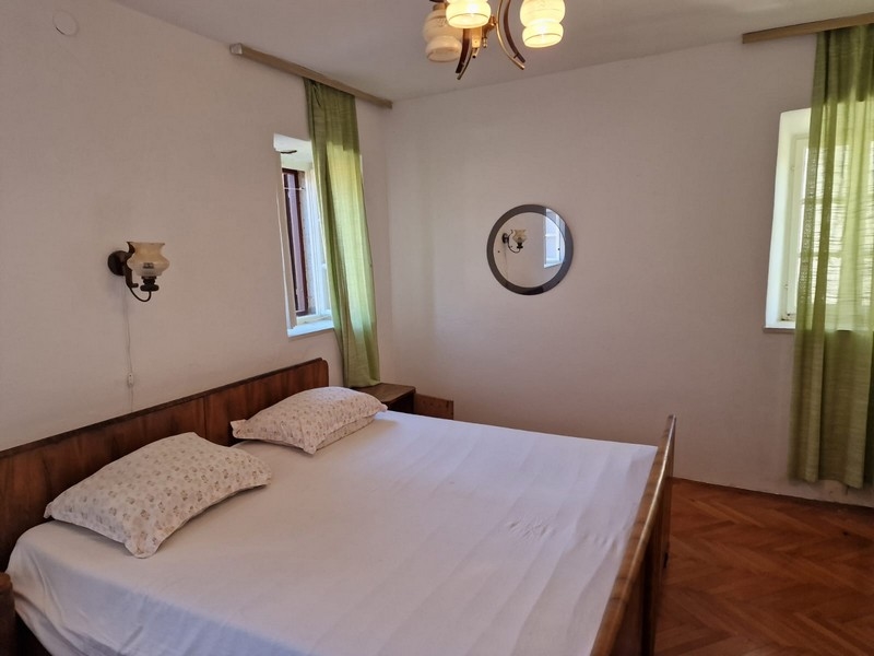 Spálňa s manželskou posteľou, dreveným rámom a zelenými závesmi