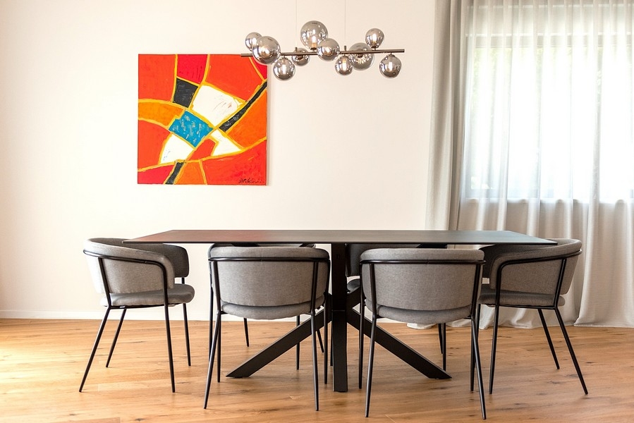 Jedálenský kút s dizajnovou lampou a veľkým umeleckým dielom na stene