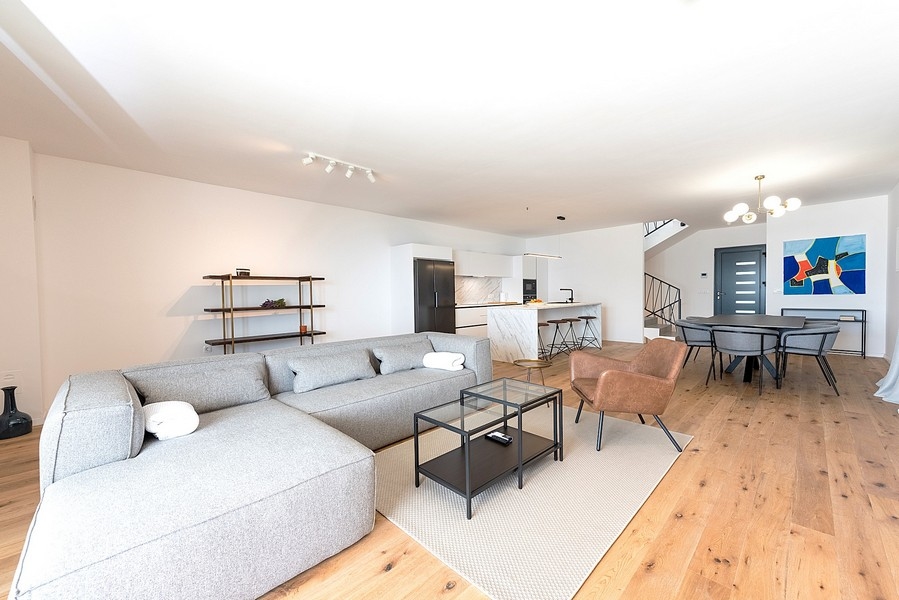 Priestranná obývacia izba s pohovkou, jedálenským kútom a schodiskom na poschodie