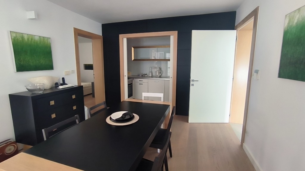 Jedáleň s tmavým stolom a prepojením na kuchyňu