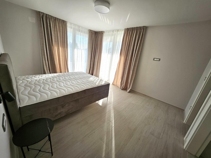 Svetlá spálňa s manželskou posteľou, závesmi a balkónovými dverami