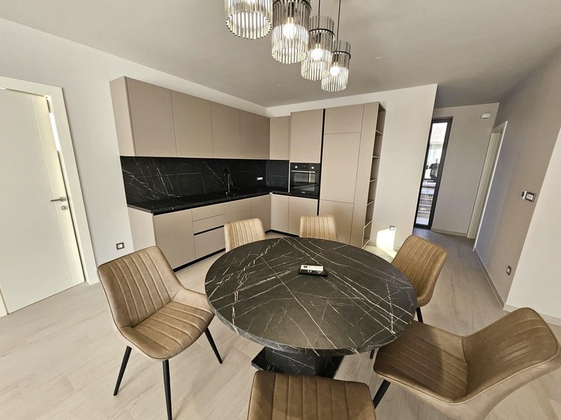 Moderná kuchyňa s čiernymi pracovnými plochami a okrúhlym jedálenským stolom