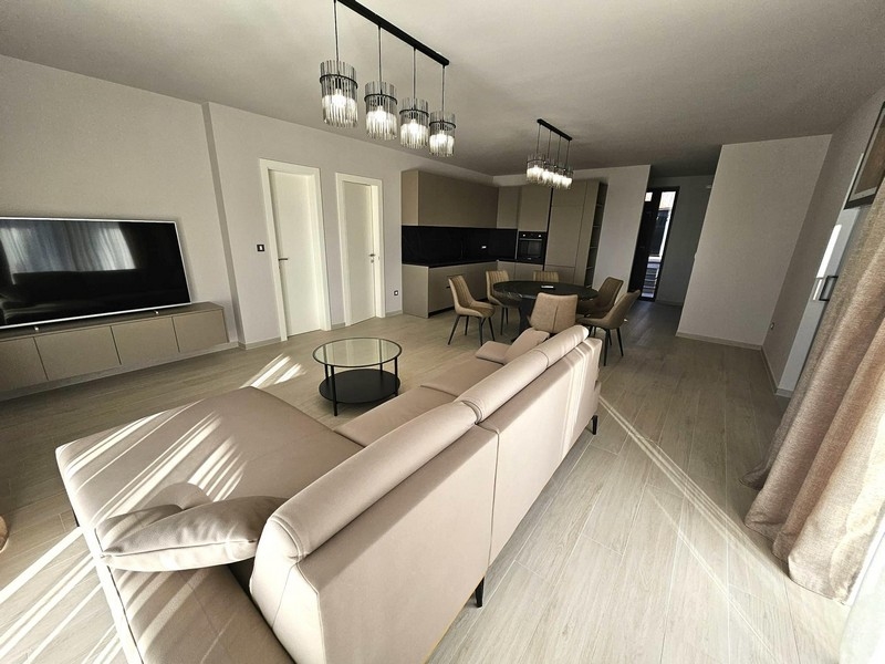 Otvorený obývací priestor s pohovkou, TV a dizajnovými lampami