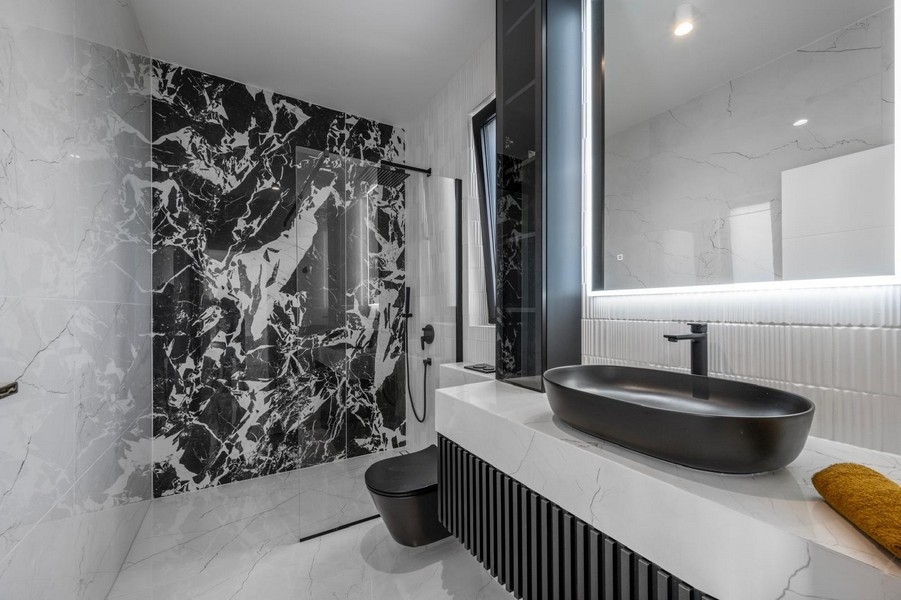 Štýlová kúpeľňa s mramorovými obkladmi a čiernym nábytkom