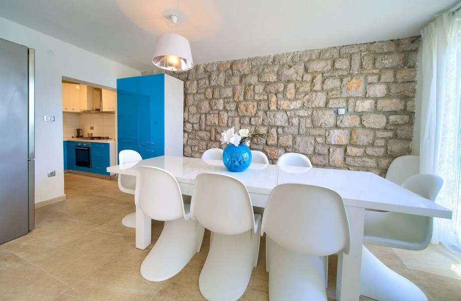 Svetlý jedálenský kút so stenou z prírodného kameňa a výhľadom do kuchyne