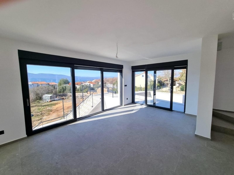 Obývacia izba s veľkým preskleným priečelím a výhľadom na more