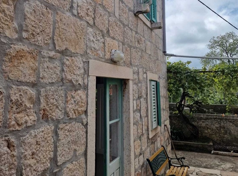 Kamenná fasáda s vchodom a okenicami