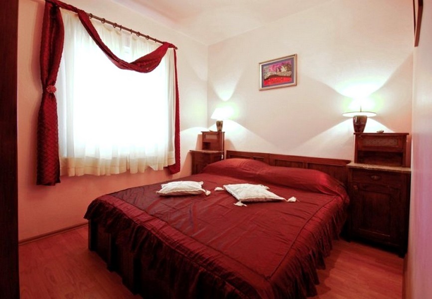 Spálňa s manželskou posteľou a červenou posteľnou bielizňou