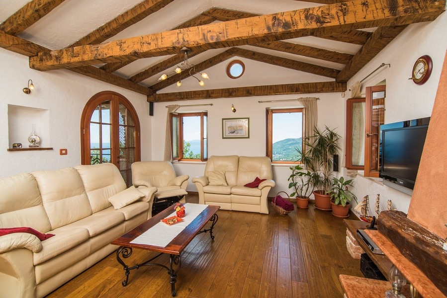 Obývacia izba s drevenými trámami a výhľadom do zelene