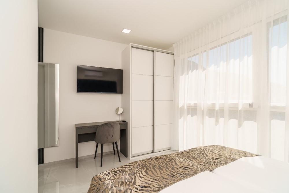 Svetlá spálňa s písacím stolom a TV