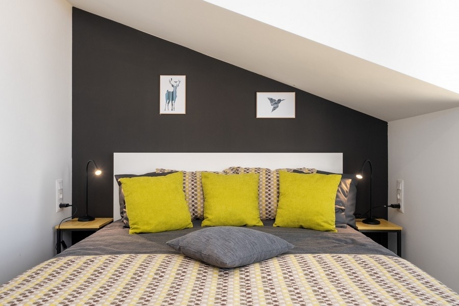 Podkrovná spálňa s manželskou posteľou a žltými vankúšmi