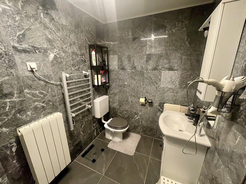 Moderná kúpeľňa so sprchovacím kútom, WC a sivými obkladmi