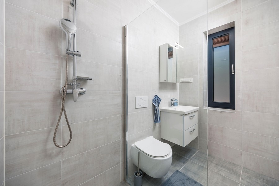 Moderná kúpeľňa so sprchovacím kútom a oknom