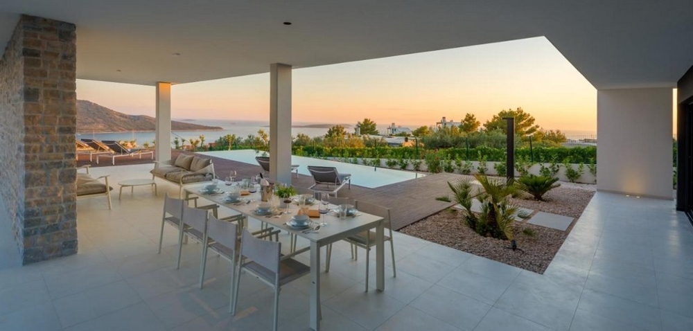 Krytá terasa s jedálenským stolom a výhľadom na more