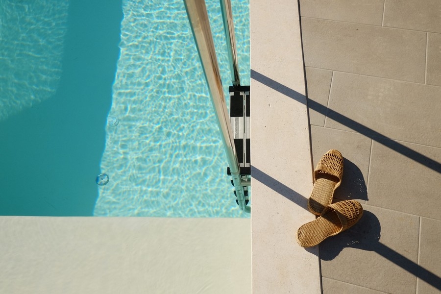 Detail bazéna so slnečným žiarením a sandálmi