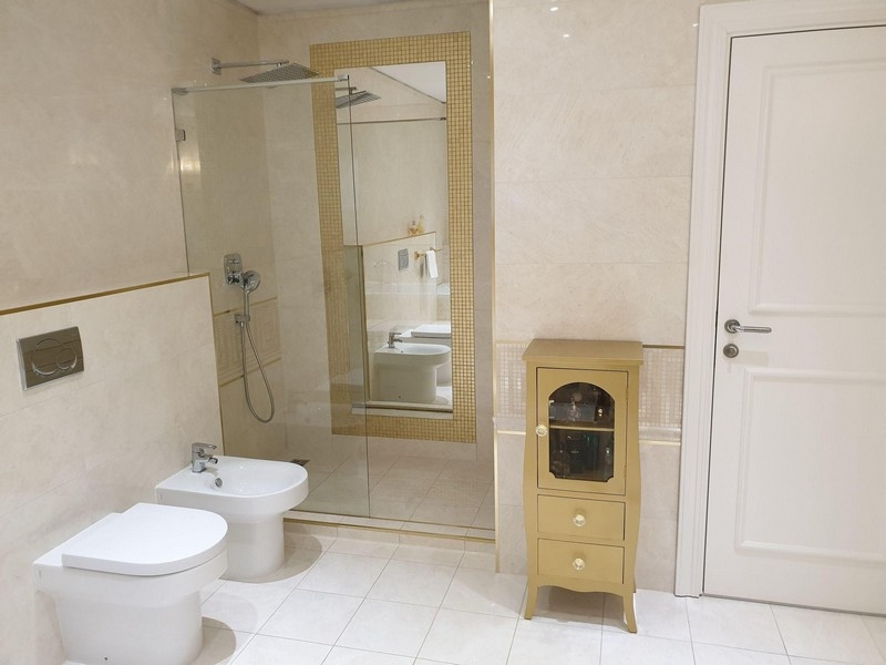 Kúpeľňa so sprchovacím kútom, bidetom a svetlou dlažbou