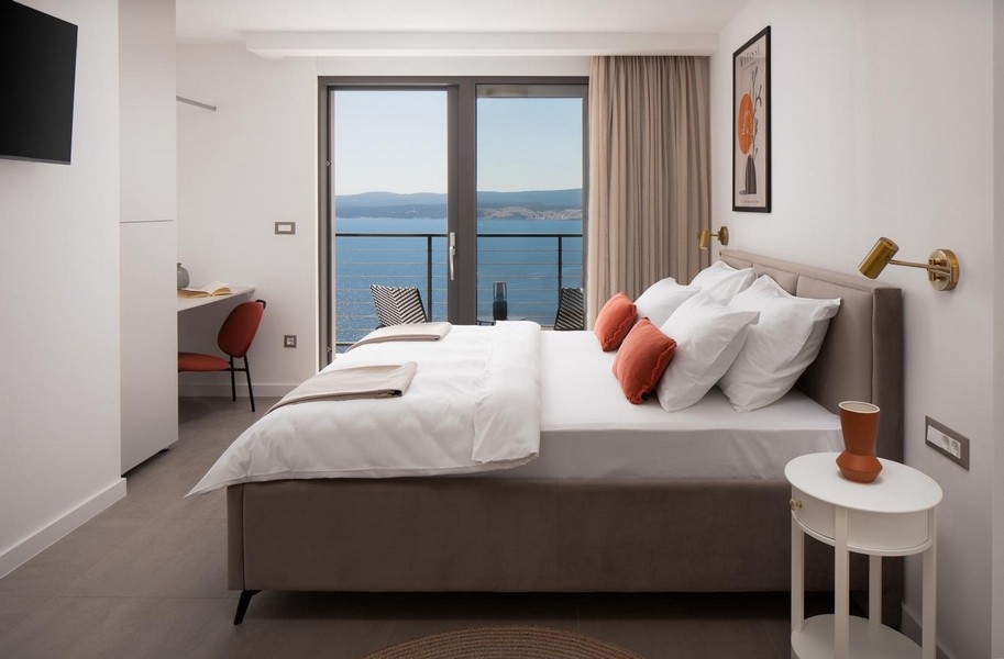 Svetlá spálňa s manželskou posteľou a výhľadom na more