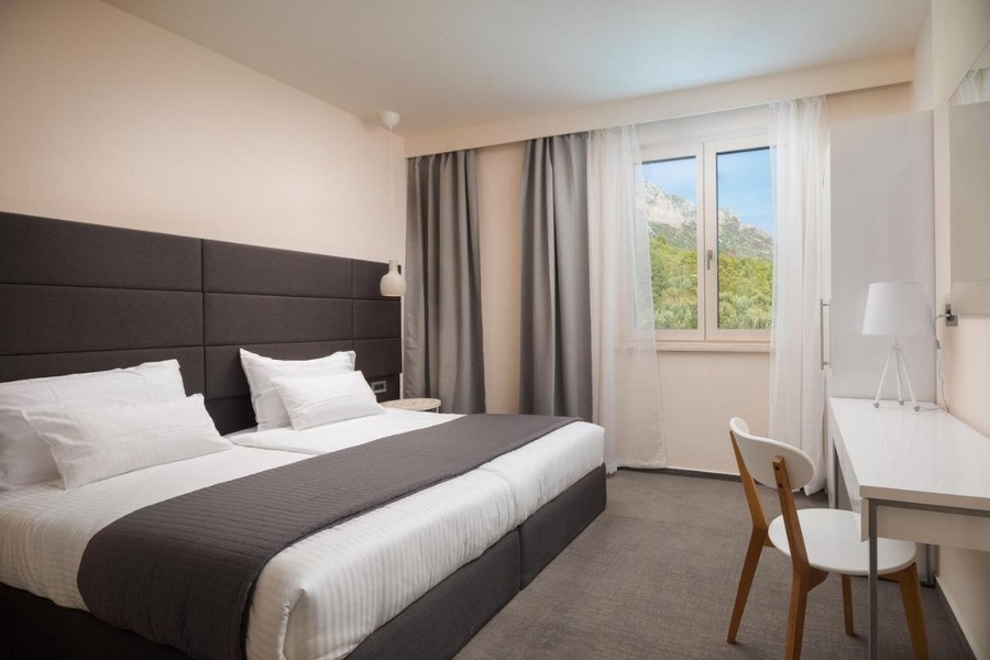 Svetlá spálňa s manželskou posteľou a výhľadom na hory