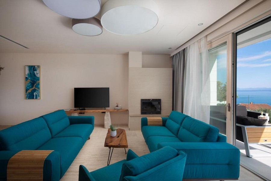 Moderná obývacia izba s modrými pohovkami a výhľadom na more