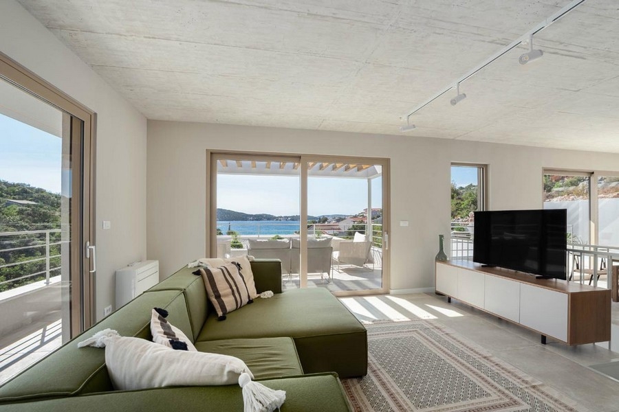 Obývacia izba s pohovkou a východom na terasu s výhľadom na more