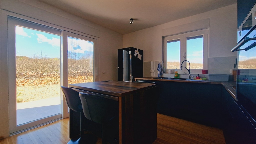 Moderná kuchyňa s kuchynským ostrovčekom a vstupom do záhrady